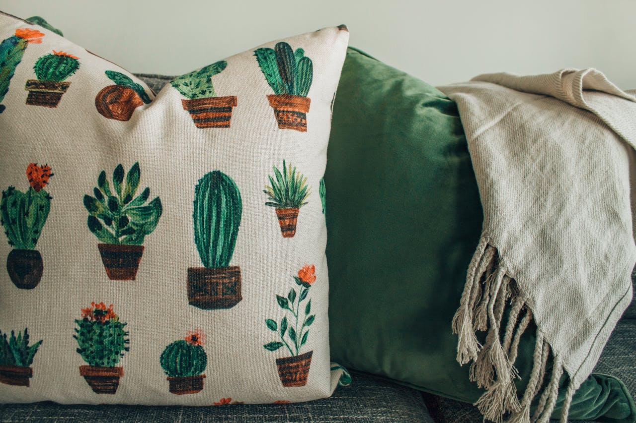 services-03 A cozy modern interior featuring cactus print throw pillows and a soft blanket on a sofa.