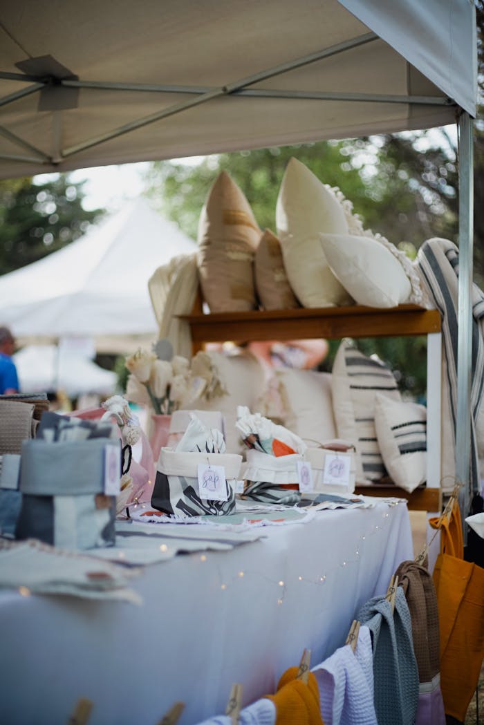A vibrant display of pillows and linens in an outdoor market setting, showcasing texture and color.