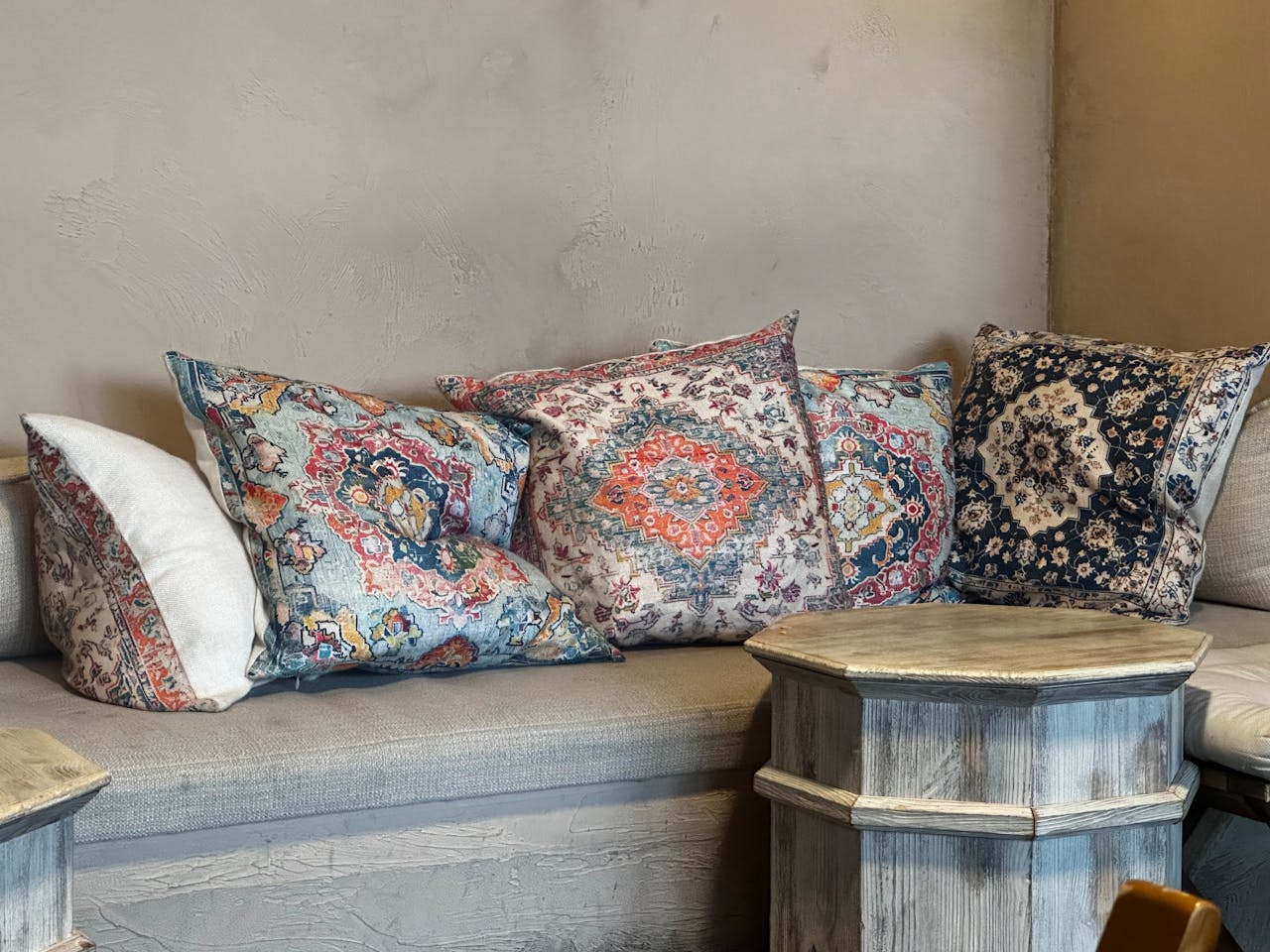 A collection of decorative patterned cushions on a rustic wooden bench, creating a cozy atmosphere.