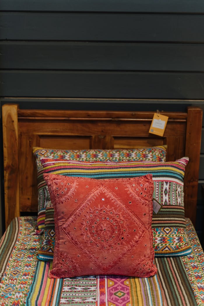 Vibrant bed setup with colorful pillows and ethnic patterns in a cozy bedroom.