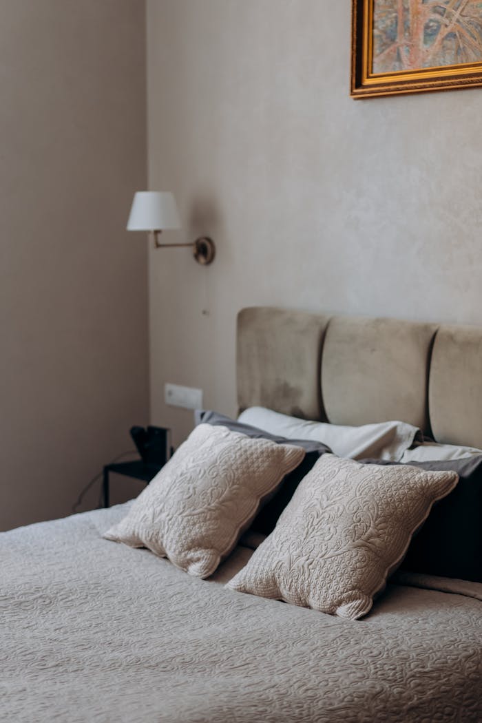 Cozy and elegant bedroom interior showcasing minimalist design with a focus on bedding and wall art.