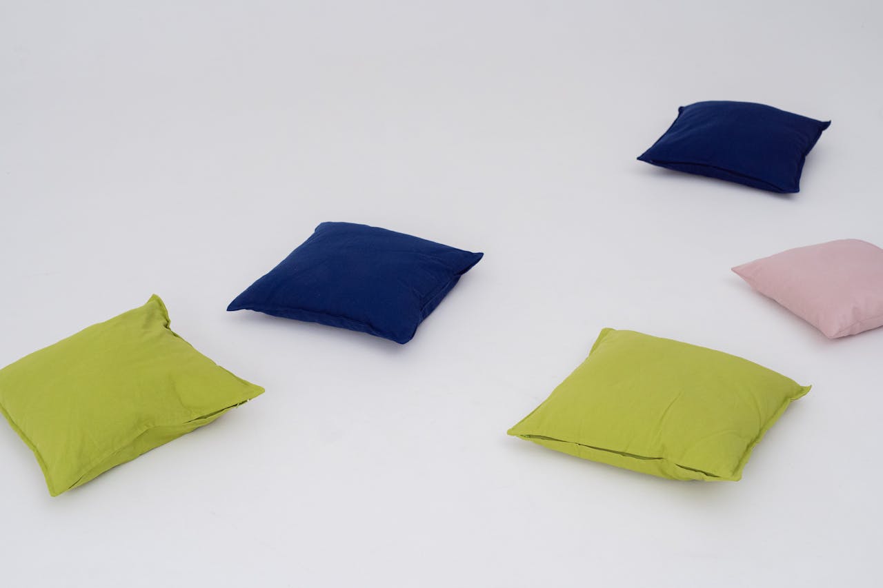 who-we-are Vibrant green, blue, and pink throw pillows spread on a white background.